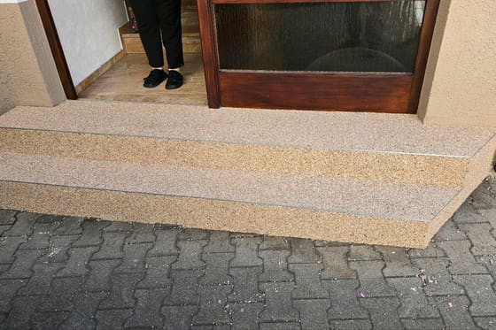 Fertig sanierte Eingangsstufen mit hellem Steinteppich, davor eine Person – Arbeit von mf.steintechnik aus Kirchheim am Neckar
